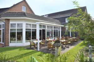 eine Terrasse mit Tischen und Stühlen vor einem Gebäude in der Unterkunft Hotel Landhaus Dierkow in Rostock