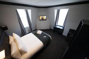 a hotel room with a bed and three windows at The Duke Rooms London in London