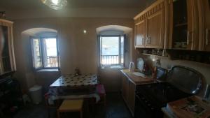 een keuken met een tafel en 2 ramen bij BellaVistaZmukic Guesthouse in Perast