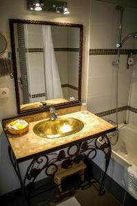 La salle de bains est pourvue d'un lavabo, d'un miroir et d'une baignoire. dans l'établissement Hotel Restaurant Le Gardon - Pont du Gard, à Collias