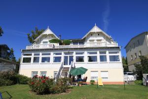 ein großes weißes Gebäude mit einem Tisch und einem Sonnenschirm in der Unterkunft Ferienwohnung Seerose mit Terrasse in Sassnitz