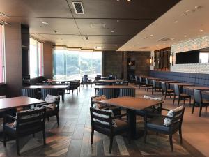 a restaurant with tables and chairs and a large window at Tanegashima Iwasaki Hotel in Minamitane
