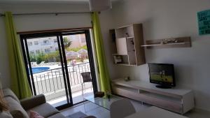 a living room with a tv and a sliding glass door at Vista das Ondas Olhos de Agua in Albufeira
