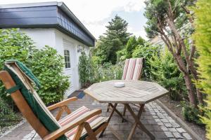 eine Terrasse mit 2 Stühlen, einem Holztisch und Stühlen in der Unterkunft Ferienwohnungen in ruhiger Ortsran in Lauterbach