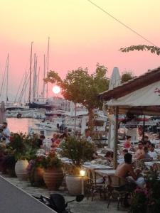 a group of people sitting at tables near a marina at Virvilis Apartments in Syvota