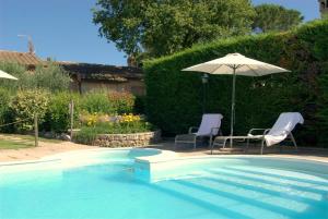 uma piscina com duas cadeiras e um guarda-sol em Agriturismo La Dolce Collina em Paciano