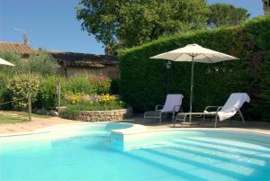 a swimming pool with two chairs and an umbrella at Agriturismo La Dolce Collina in Paciano