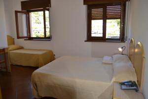 a bedroom with a bed and a chair and two windows at A Casa Di Luca in Diamante