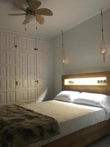 Villa Dolce Vita في بالاموس: غرفة نوم مع سرير ومروحة سقف