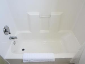 a bathroom with a white bath tub with a towel at El Rancho Inn in Hawthorne +30 photos
