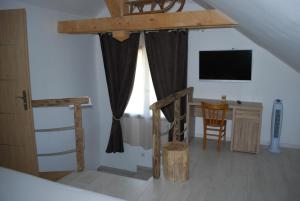 une chambre avec un lit et un bureau avec une télévision dans l'établissement La ferme de Coron, à Belley