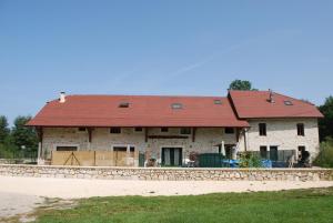 een groot stenen huis met een rood dak bij La ferme de Coron in Belley