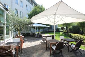 eine Terrasse mit Tischen, Stühlen und einem Sonnenschirm in der Unterkunft Hansa Apart-Hotel Regensburg in Regensburg