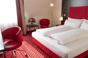 a hotel room with two beds and a red chair at Best Western Plaza Hotel Wels in Wels