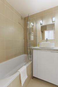 een badkamer met een wastafel, een bad en een spiegel bij Apartment Jonquille Terrasse in Chamonix-Mont-Blanc