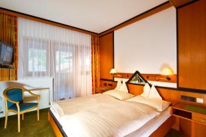 a bedroom with a bed and a chair and a window at Hotel Mathiesn in Obergurgl