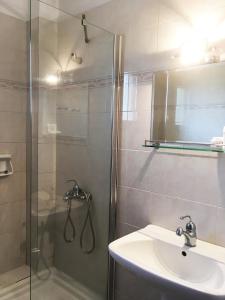 uma casa de banho com um chuveiro, um lavatório e um espelho. em Doviros Hotel em Doirani