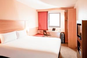 ein Hotelzimmer mit einem Bett, einem Schreibtisch und einem Fenster in der Unterkunft ibis London Elstree Borehamwood in Borehamwood