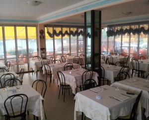 a restaurant with white tables and chairs and windows at Acquamarina B&B in Martinsicuro