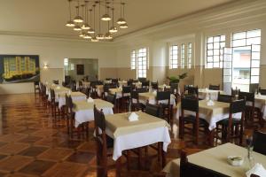 a large dining room with tables and chairs with white linen at Hotel Metropole in Belo Horizonte