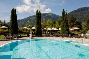 a pool at a resort with mountains in the background at Schlosshotel Kitzbühel A-ROSA Collection in Kitzbühel