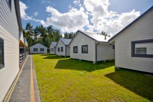 a row of white houses in a yard at Bursztynowo Domki Letniskowe in Ostrowo