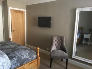 a bedroom with a chair and a mirror and a tv at 1 St Ellas House Apartment in Eyemouth