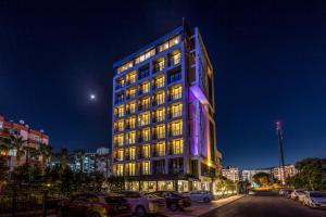 a lit up building with cars parked in a parking lot at Vista Hotel in Mezitli