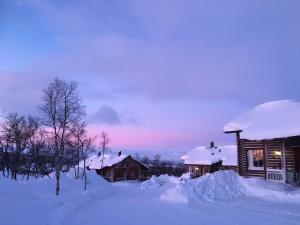 Cabaña de madera en la nieve con techo cubierto de nieve en Kilpisjärven Tunturimajat en Kilpisjärvi