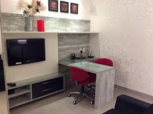 Habitación con escritorio, TV y silla roja. en Condo Ipanema 503, en Río de Janeiro