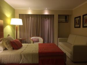 a hotel room with a bed and a couch at Condado Hotel Casino Paso de la Patria in Paso de la Patria