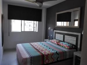 a bedroom with a bed and a mirror and windows at Apartamento Estació in Torredembarra