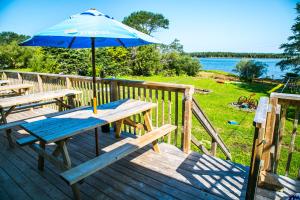 a picnic table with an umbrella on a deck at Groundswell Pub & Inn in DʼEscousse