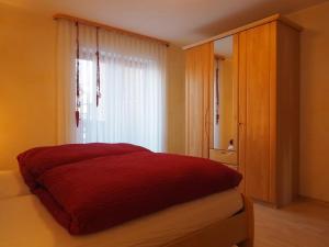 1 dormitorio con cama roja y ventana en Ferienwohnung Herbst, en Edelsfeld