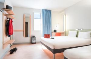 a hotel room with two beds and a cat laying on the floor at ibis Budget Bobigny Pantin in Bobigny
