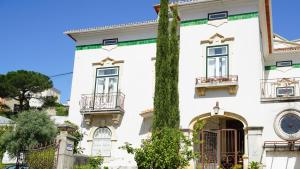 a white house with a tree in front of it at Adore Portugal Coimbra Guest House in Coimbra