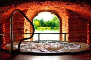 a bath tub in a brick building with a window at Hôtel & Spa Le Moulin de Moissac in Moissac