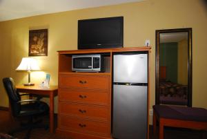 a room with a refrigerator and a television on top of a dresser at Coach Light Inn in Brenham