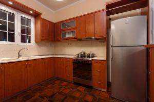 a kitchen with wooden cabinets and a stainless steel refrigerator at Metropolis Apartment in Zakynthos Town