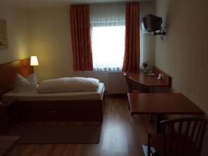a hotel room with a bed and a desk and a window at Hotel am Exerzierplatz in Mannheim