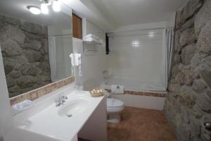 baño con lavabo y aseo con pared de piedra. en Siete Ventanas, en Cusco