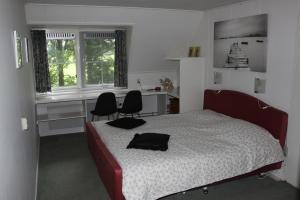 een slaapkamer met een bed en 2 stoelen en een bureau bij B&B 't Hekkert in Gorssel