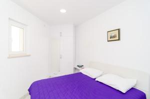 ein weißes Zimmer mit einem lila Bett und einem Fenster in der Unterkunft Apartment Riki in Dubrovnik