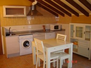 a kitchen with a table and a sink and a washing machine at Apartamentos Antonio in Ubiarco