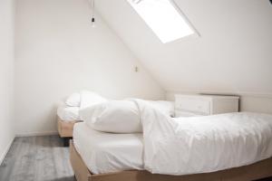 1 dormitorio con 2 camas con sábanas blancas y ventana en Since 89 guesthouse close to the beach, en Katwijk aan Zee
