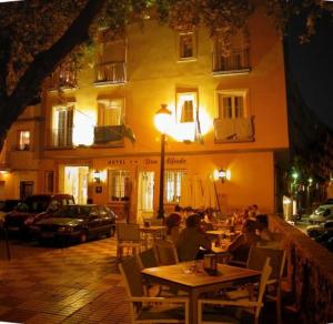 馬貝拉的住宿－唐阿爾弗雷多酒店，夜间坐在餐厅外桌子上的人