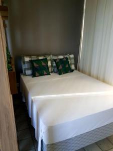 a large white bed with green pillows in a room at Aconchegante Flat na Orla in Recife