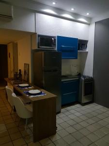 a kitchen with blue cabinets and a black refrigerator at Aconchegante Flat na Orla in Recife