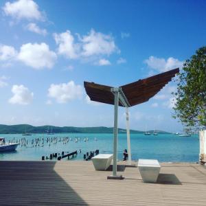 a wooden boardwalk with a beach with people in the water at Parador Boquemar in Boqueron