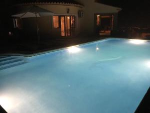 una gran piscina por la noche con sombrilla en Casa Canela en Monte Pego